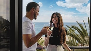 Ein Paar genießt ein Glas Wein mit Meerblick auf dem Balkon – Teil des Barcelona F1 Tickets Pakets zum Spanien GP