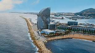 Strandkulisse mit Meerblick und Gebäuden – die perfekte Atmosphäre für ein Wochenende mit F1 Barcelona 2025 Tickets