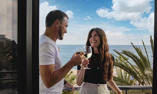 Paar genießt Hotelbalkon mit Meerblick während MotoGP Reise