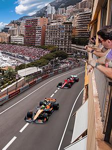 Formel-1-Autos rasen über den Stadtkurs von Monaco, während Fans von den Balkonen zuschauen.