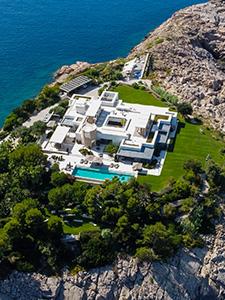Luftaufnahme einer luxuriösen Privatvilla mit Pool und Meerzugang, umgeben von Grünflächen.