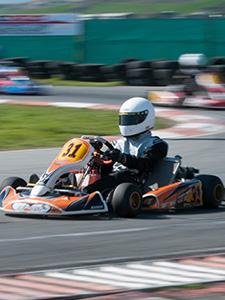 Piloto compitiendo en una pista de karting durante una actividad de equipo intensa.