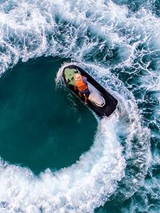 Person auf einem Jetski in einer scharfen Kurve über türkisblauem Wasser.