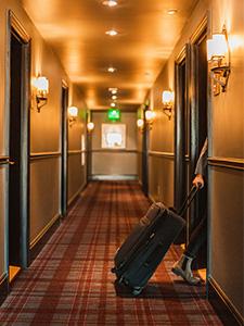 Persona con maleta entrando a una habitación en el pasillo de un hostal.