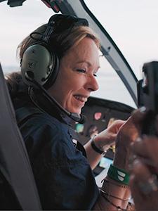 Lächelnder Gast mit Headset während eines Rundflugs im Helikopter.