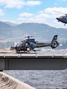 Hubschrauber auf einem Landeplatz mit Küstengebirge im Hintergrund.