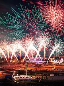 Fuegos artificiales de colores iluminan el cielo nocturno sobre el recinto del espectáculo.