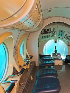 Innenraum eines U-Boots mit Sichtfenstern und Sitzplätzen.