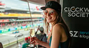 Una emocionada fan femenina de Fórmula 1 con una copa de champán en la tribuna Global-Tickets Mavericks Club durante una carrera